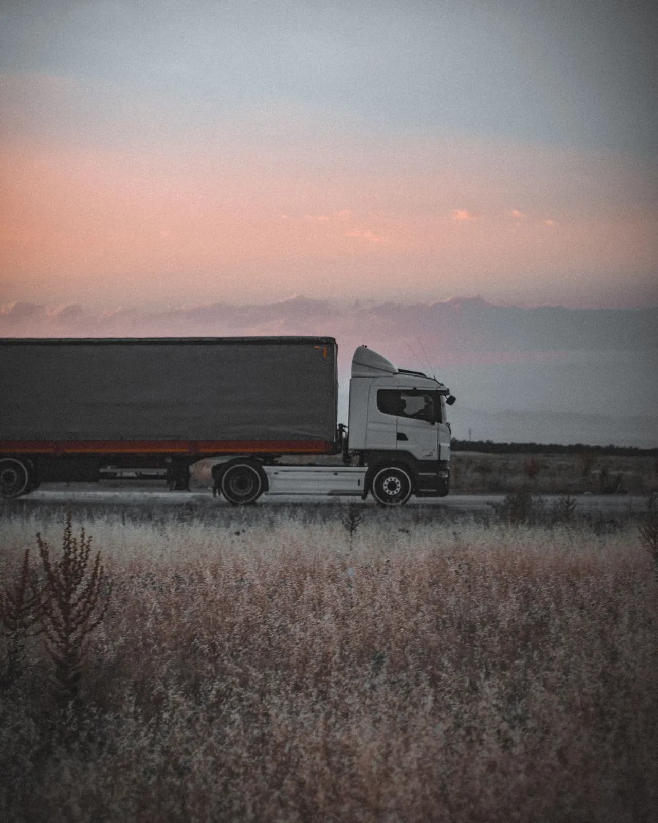 Cargo truck travelling on an open highway at dusk