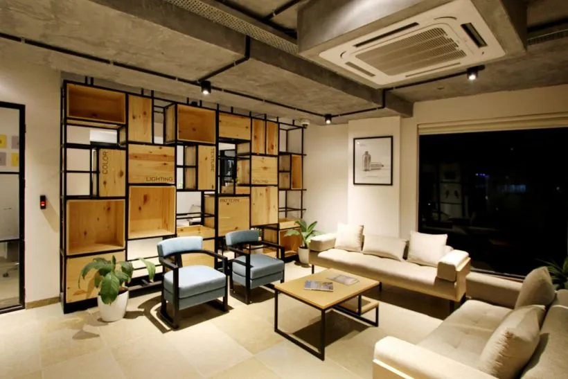 Clean, modern office lounge with sofas, armchairs and wooden shelving