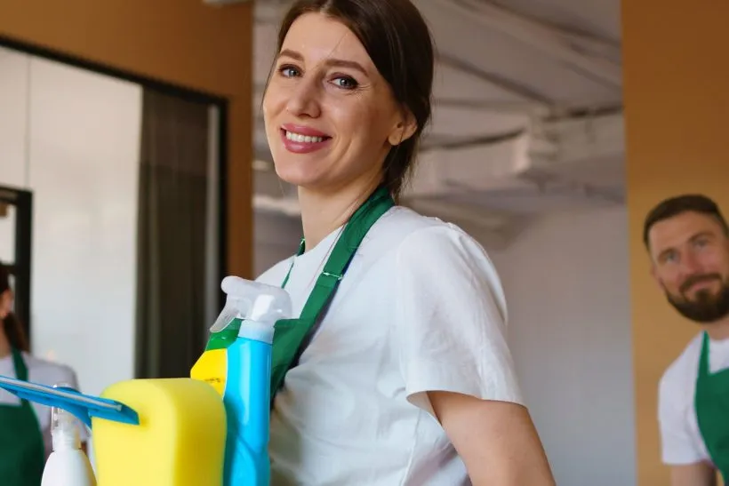 Cleaner carrying spray bottles and cleaning supplies into a home