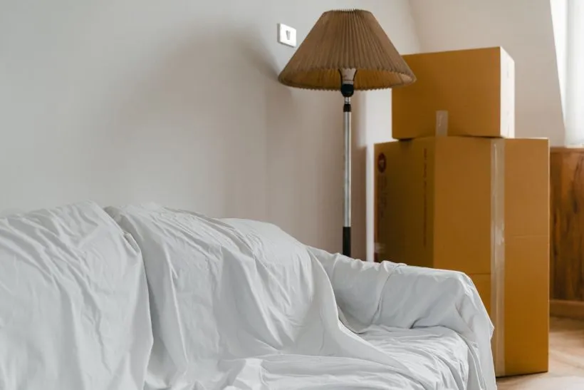 Packed cardboard boxes stacked beside a sofa covered with a protective sheet, ready for a house move